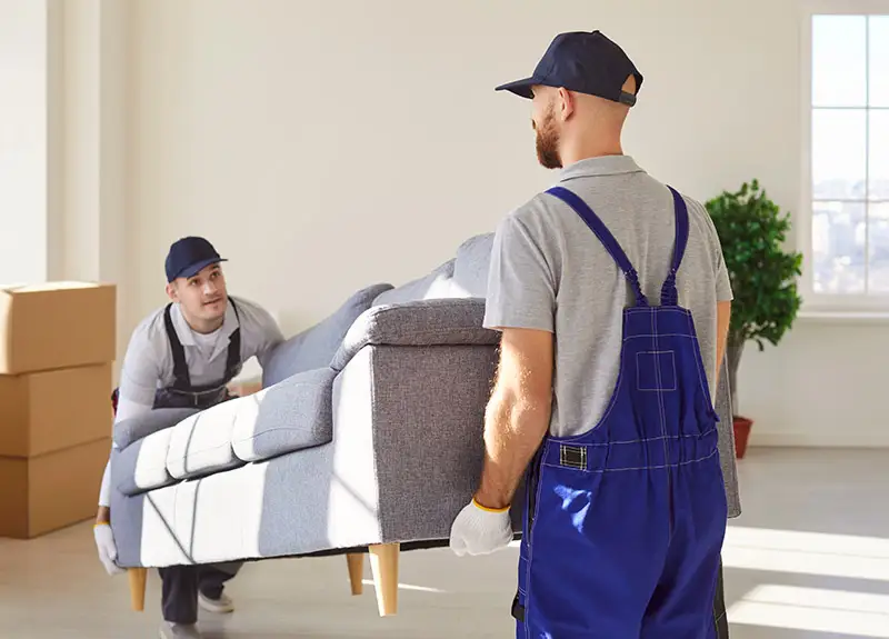 Zwei Umzugsprofis tragen eine schwere Couch
