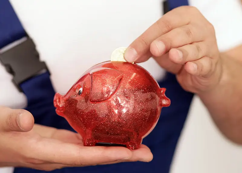 Ein Umzugshelfer steckt eine Münze in ein rotes Sparschwein