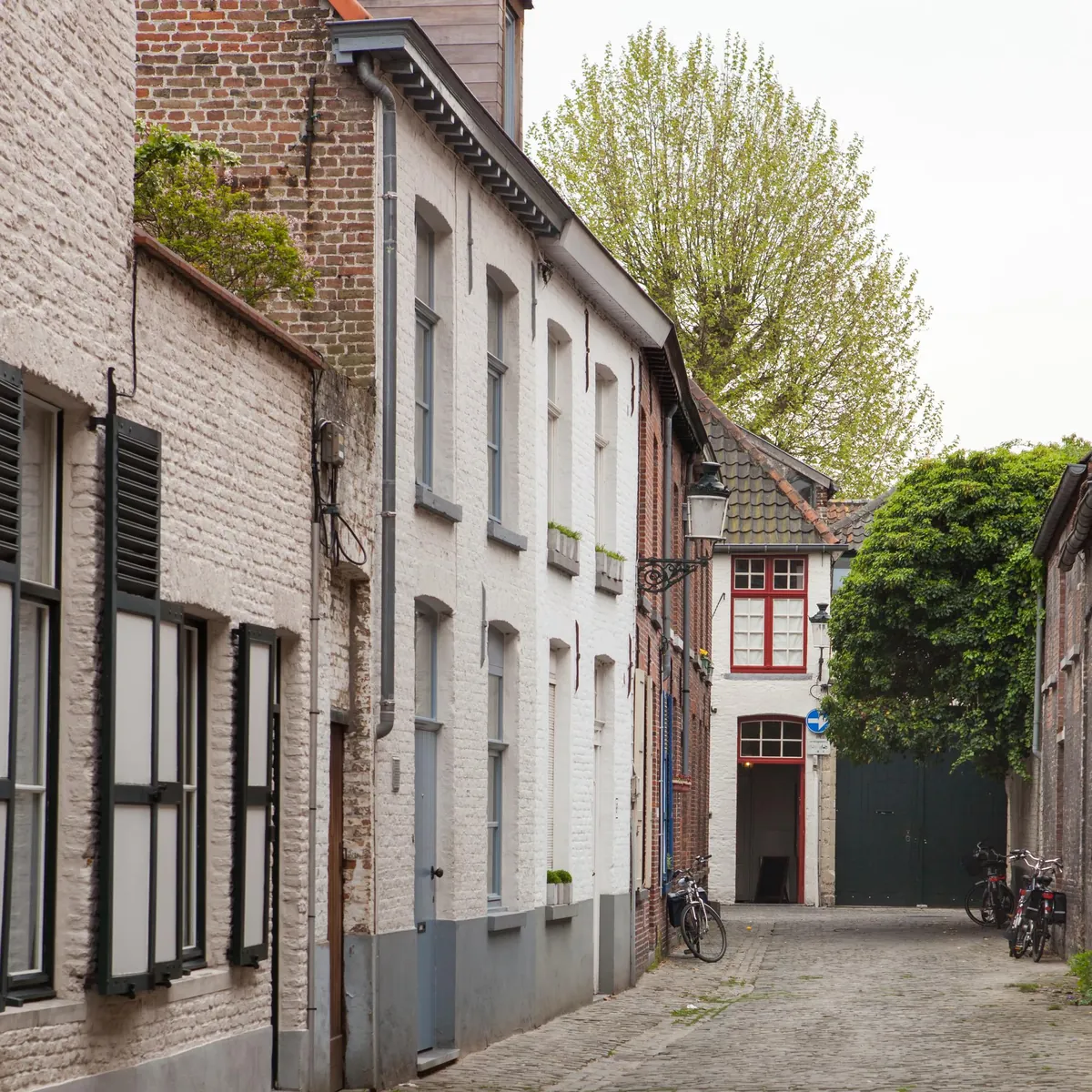 Kopfsteinpflastergasse mit weißen Backsteinhäusern und Fahrrädern.