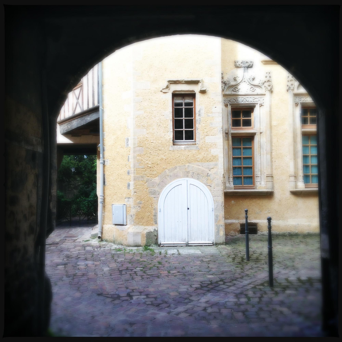 Blick durch einen Torbogen auf ein historisches Steingebäude.