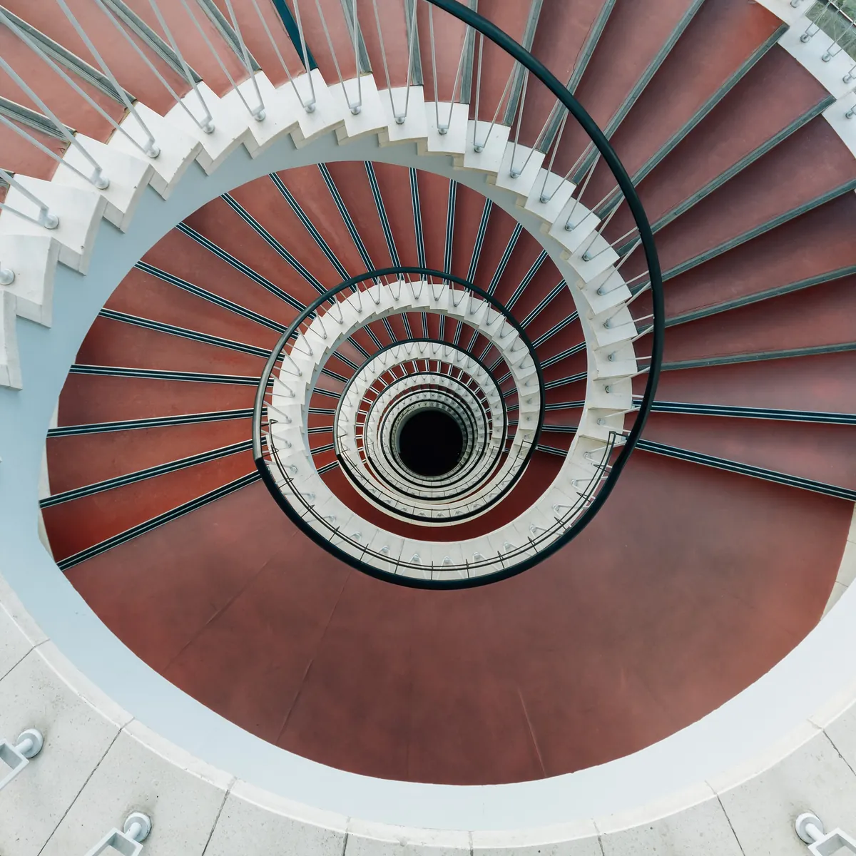 Vogelperspektive einer spiralförmigen Wendeltreppe mit rotem Boden.